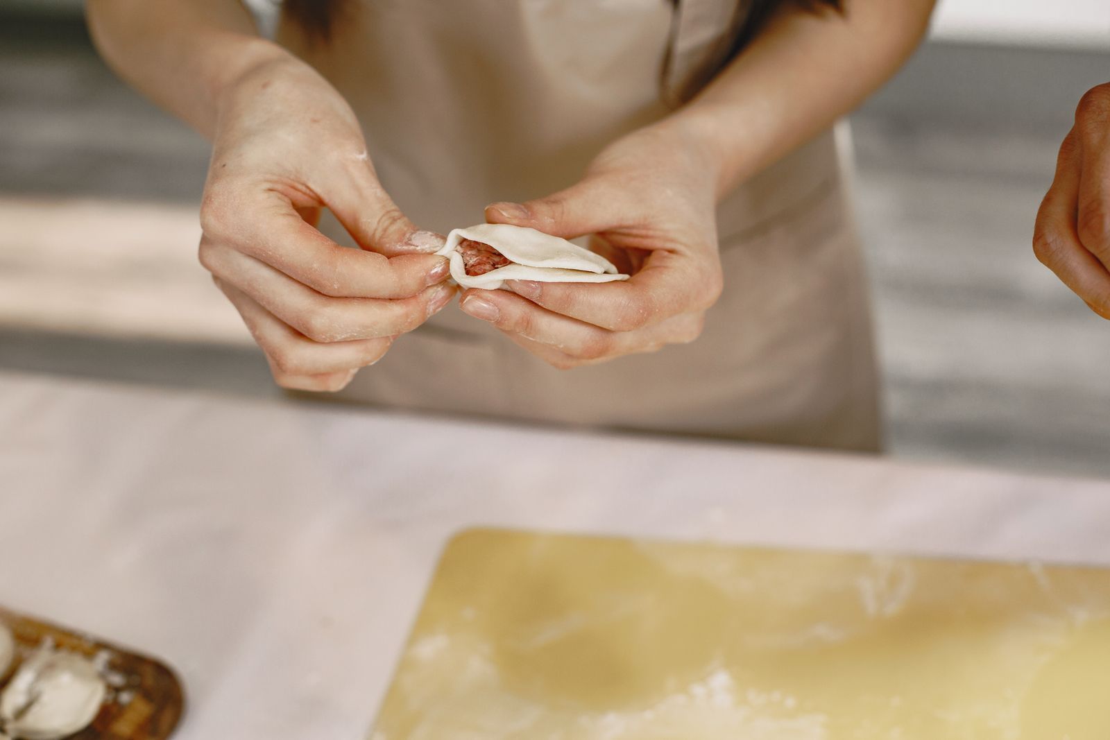 Mani che chiudono la pasta ripiena sul tavolo infarinato